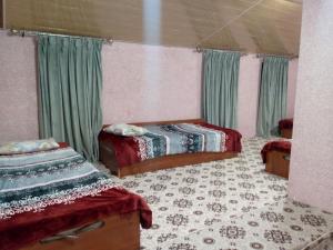 a bedroom with two beds and green curtains at Гостевой дом Нилюфар in Kyzyldzhar