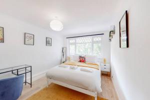 a white bedroom with a bed and a window at Modern 4BD house with a private patio in Islington in London