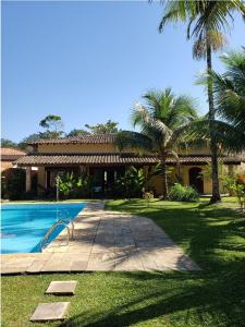 a house with a swimming pool and palm trees at Casa Praia Jardim Acapulco in Guarujá