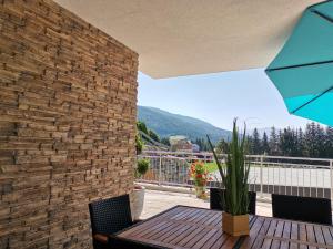 un patio con tavolo, sedie e muro di mattoni di Berg:Zeit_Apartments a Tamsweg