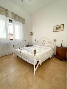 ein Schlafzimmer mit einem weißen Bett in einem Zimmer in der Unterkunft Viareggio ampia casa con giardino in Viareggio