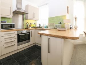 a kitchen with white cabinets and a wooden counter top at Y Castell Apartment 2 in Porthmadog