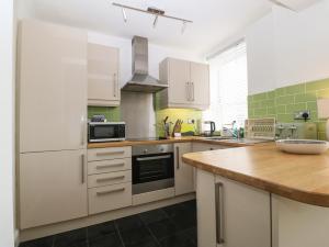 a kitchen with white appliances and a wooden counter top at Y Castell Apartment 2 in Porthmadog