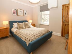 a bedroom with a blue bed and a window at Y Castell Apartment 2 in Porthmadog