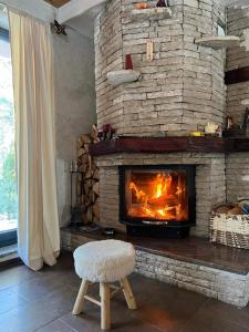 - un salon avec une cheminée en pierre et un tabouret dans l'établissement Snježna vikendica, à Risovac