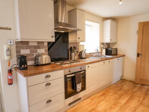 a kitchen with white cabinets and a wooden floor at Coopers Cottage in Whitby