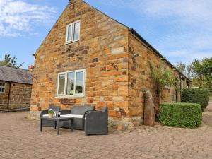 a brick building with two chairs and a table in front of it at Coopers Cottage in Whitby