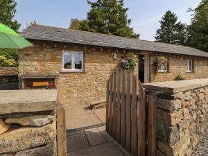 a stone house with a wooden gate in front of it at Stable Cottage in Burton in Lonsdale