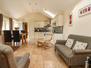 ein Wohnzimmer mit 2 Sofas und einer Küche in der Unterkunft Stable Cottage in Burton in Lonsdale