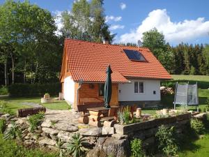 een klein huis met een oranje dak en een tuin bij Chata Venda in Lipno nad Vltavou