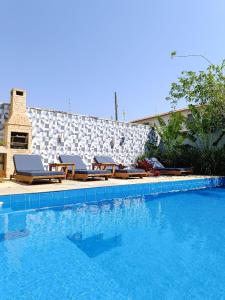 a swimming pool with lounge chairs next to a stone wall at Casa Azul Hibisco - Geriba Buzios in Búzios