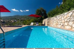 a swimming pool with two chairs and a red umbrella at Villa Capra Verde in Ičići