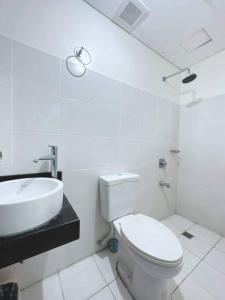 a white bathroom with a toilet and a sink at Blessed Condo for 6 - include net, water & electric in Manila