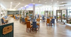 a restaurant with tables and chairs in a room with windows at Cedar Court Bradford Hotel in Bradford