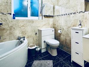 a bathroom with a toilet and a tub and a sink at Zoya’s Place in Harrow in Pinner