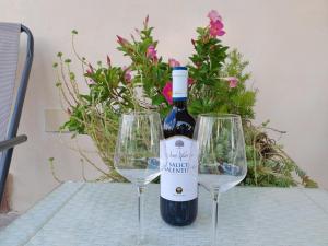 una bottiglia di vino e due bicchieri di vino su un tavolo di Casa in campagna ⋅ ForiMìa a San Vito dei Normanni