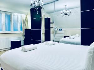 a bedroom with two white beds with blue walls at Zoya’s Place in Harrow in Pinner