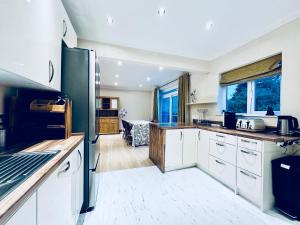 a kitchen with white cabinets and a black refrigerator at Zoya’s Place in Harrow in Pinner