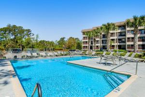 a swimming pool with chairs and a building in the background at HH Beach & Tennis 132C in Hilton Head Island