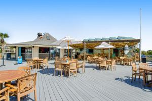 an outdoor patio with tables and chairs and umbrellas at HH Beach & Tennis 132C in Hilton Head Island