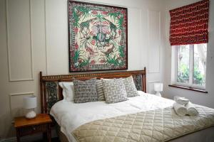 1 dormitorio con 1 cama con una pintura en la pared en The Spirit of the Cape, en Ciudad del Cabo