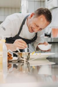 Um chef está a preparar comida numa cozinha. em Hotel Arlberg Lech em Lech am Arlberg