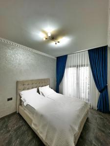 a bedroom with a large white bed with blue curtains at Casa Anastasia in Oradea