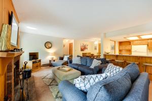 a living room with two blue couches and a kitchen at Riverfront Lincoln Condo with Pool Mins to Loon Mtn in Lincoln
