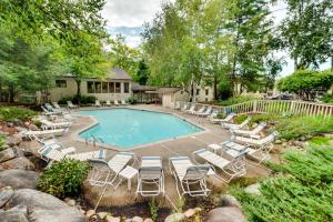 a swimming pool with lounge chairs and a house at Riverfront Lincoln Condo with Pool Mins to Loon Mtn in Lincoln