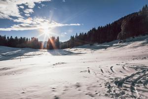 a snow covered field with the sun in the sky at Hasenalm in Schliersee