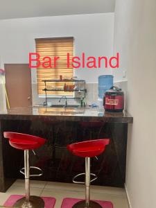 un'isola bar con sgabelli rossi di fronte a un bancone di Empire Homestay Melaka a Malacca