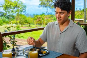 a man sitting at a table with a plate of food at Galapagos Cabañas Eden in Bellavista