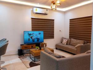 uma sala de estar com um sofá e uma televisão de ecrã plano em LAKESIDe VILLA em Acra