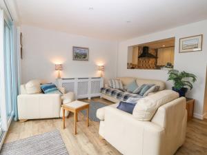 una sala de estar con 2 sofás blancos y una mesa. en Angorfa, en Beaumaris