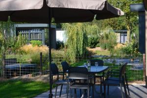 una mesa y sillas bajo una sombrilla en un patio en 6 persoons bungalow met omheining van de tuin vlakbij Walibi en Biddinghuizen