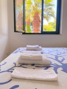 a group of towels sitting on a bed with a window at Rais Gerbi Appartamento in Pollina
