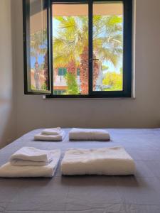a bed with four towels on it with a window at Rais Gerbi Appartamento in Pollina