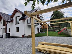 um banco de madeira em frente a uma casa com um parque infantil em APARTAMENTY UL.SARNIA em Wisla