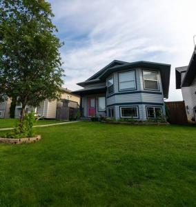 una casa azul en un jardín en Pink door-ed wonder, en Grande Prairie