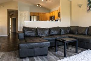 a living room with a leather couch and a table at Pink door-ed wonder in Grande Prairie