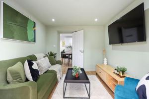a living room with a green couch and a flat screen tv at Camden Garden Apartments in London