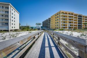 a boardwalk over the sand at the beach with buildings at Okaloosa Island Condo Near Boardwalk and Beach! in Fort Walton Beach