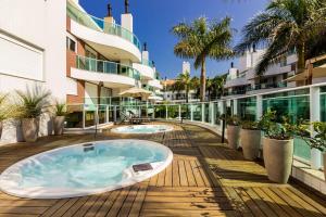 Un jacuzzi en una terraza junto a un edificio. en Boulevard 310D - Excelente Cobertura com Jacuzzi Privativa em condomínio de luxo no centro de Bombinhas - Piscina - Jacuzzi - Academia - Portaria 24h., en Bombinhas