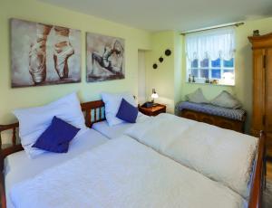- une chambre avec 2 lits blancs et des oreillers bleus dans l'établissement Ferienwohnung mit ländlichem Charme, à Rodgau