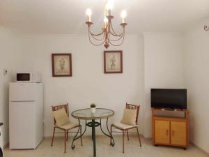 ベナルマデナにあるCoqueto estudio en Calle Velaのテーブルと椅子、テレビが備わる客室です。