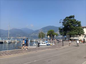 Eine Gruppe von Menschen, die auf einem Gehweg in der Nähe eines Gewässers spazieren gehen in der Unterkunft Beth House Iseo in Iseo