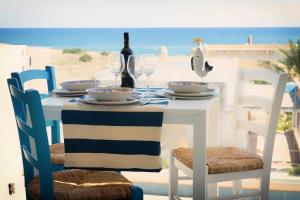 een tafel met stoelen en een tafel met wijnflessen en glazen bij Vela Bianca Marzamemi in Marzamemi