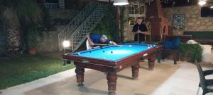 a man sitting in a chair next to a pool table at Dolphin Apartments in Fethiye