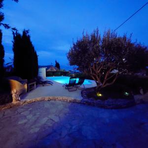 a swimming pool at night with two chairs in a yard at Charming Villa Nika with the pool in Supetar
