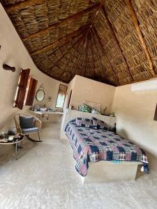 1 dormitorio con cama y techo de paja en Cabañas HUNAB KU 21, 